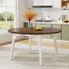 A round dining table with a brown wooden top and white legs, set in a kitchen with green cabinets and a large window. Náhľad obrázku produktu
