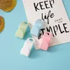 Four plastic hooks in different colors are arranged on a light blue background with a white card featuring text. Produktbild-Vorschau