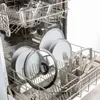 A dishwasher rack filled with clean dishes, including plates, glasses, and cutlery. Voir les images du produit
