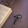 A Bluetooth headset, a book, and glasses are placed on a wooden table. Produktbild-Vorschau