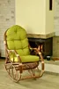 A rocking chair with a green cushion is placed next to a fireplace. Anteprima dell’immagine prodotto