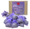 A box of lavender sachets with a bunch of lavender flowers and a pile of sachets in front. Produktbild-Vorschau