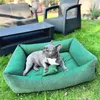 A French bulldog lies on a green dog bed in a grassy backyard with outdoor furniture in the background. Náhled obrázku produktu