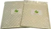 Two square items are packaged in clear plastic bags, each with a label featuring a green clover and text. Produktbild-Vorschau