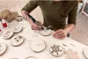 A person is using a Dremel tool to engrave designs onto wooden discs. Anteprima dell’immagine prodotto