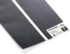 A close-up, angled view of a black heating mat with two white stripes, partially covered by a clear plastic packaging. Anteprima dell’immagine prodotto
