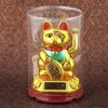 A golden lucky cat figurine in a clear plastic case, sitting on a red base with a solar panel. Produktbild-Vorschau