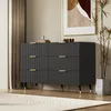 A modern black dresser with gold accents is shown in a well-lit room with a large abstract painting on the wall and a potted plant. Podgląd zdjęcia produktu