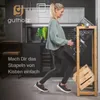 A woman is placing a black crate into a wooden shelving unit designed for beverage crates. Produktbild-Vorschau