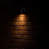 A wall-mounted outdoor light fixture illuminates a brick wall. Produktbild-Vorschau