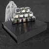 A set of stainless steel whiskey stones stacked in a pyramid on a black box, with a grey drawstring bag to the left. Produktbild-Vorschau