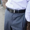 A man wearing a striped shirt and pinstripe pants, with a black leather belt and silver buckle. Anteprima dell’immagine prodotto