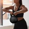 A woman is performing a kettlebell exercise in a gym. Náhľad obrázku produktu