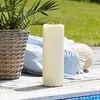 A large LED candle sits on a wooden deck next to a potted plant and a blue blanket. Podgląd zdjęcia produktu