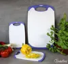 Three cutting boards of different sizes are arranged on a gray surface, with some vegetables and a plant in the background. Anteprima dell’immagine prodotto