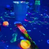 A close-up shot of neon paints and a paintbrush on a blue surface, illuminated by blacklight. Náhľad obrázku produktu
