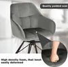 A close-up of a gray velvet chair with a hand pressing into the seat, highlighting its padding. Produktbild-Vorschau