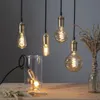 Several decorative Edison-style LED light bulbs with spiral filaments hang from black cords, with one bulb inside a glass jar on a wooden table. Podgląd zdjęcia produktu