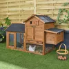 A wooden chicken coop with a run, set up on artificial grass in a backyard with a wooden fence in the background. There are two chickens visible inside the coop and a basket of eggs next to it. Anteprima dell’immagine prodotto