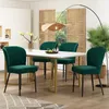 A dining room set with a marble-top table and four green velvet chairs, set against a backdrop of wooden room dividers and a large plant. Produktbild-Vorschau