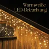 A wooden house exterior at night, decorated with warm white LED icicle lights along the roofline and window. Anteprima dell’immagine prodotto