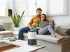 A couple relaxing on a couch in a living room, looking at a tablet, with an air purifier on a coffee table in the foreground. Voir les images du produit