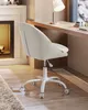A white office chair is placed on a wooden floor next to a fireplace and a desk with a lamp. Produktbild-Vorschau