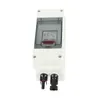 A white electrical enclosure with a transparent lid, showing a red switch and some text inside. Two black connectors are visible at the bottom. Náhled obrázku produktu