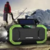 A person is standing on a mountain peak, looking out at the scenery, with a solar-powered radio in the foreground. Podgląd zdjęcia produktu