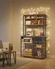 A coffee station shelving unit is set up in a living room, complete with a coffee maker, microwave, and various coffee-related items. Fairy lights are strung around the unit and along the wall. Náhled obrázku produktu