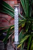 A thermometer standing in a garden with plants and a brick wall in the background. Produktbild-Vorschau