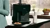 A person is standing next to a Siemens espresso machine in a kitchen setting. Náhled obrázku produktu