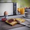 A breakfast scene with a toaster, toast with jam, an egg in an egg cup, orange juice, and coffee. Produktbild-Vorschau