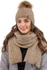 A woman wearing a beige knitted hat with a pom-pom and a matching scarf. Náhled obrázku produktu