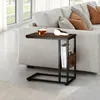 A side table with books and a cup of tea next to a sofa. Voir les images du produit