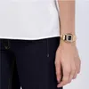 A person wearing a gold Casio Vintage watch on their wrist, paired with a white top and dark denim jeans. Podgląd zdjęcia produktu
