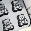 A close-up view of a baking mold with multiple bear-shaped cavities, set against a speckled gray and white background. Voir les images du produit