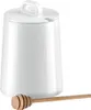 A white ceramic honey pot with a wooden honey dipper in front of it, set against a white background. Produktbild-Vorschau