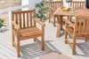 A teak wood garden chair and table set on a wooden deck, with plants in the background. Produktbild-Vorschau