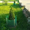 A young tree is protected by a green mesh fence in a grassy area next to a stone wall. Produktbild-Vorschau