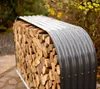 A stack of firewood covered by a curved metal roof, placed outdoors. Náhled obrázku produktu