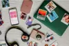 A collection of personal electronic devices and printed photos arranged on a textured surface. Podgląd zdjęcia produktu