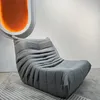 A grey beanbag chair on a striped rug in front of a white wall with a large orange oval art piece. Produktbild-Vorschau