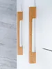 Close-up of two cabinet handles on a white cabinet, with a blurred background of light gray wood-like texture. Produktbild-Vorschau