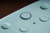 A close-up view of a mint green game controller with several buttons visible. Produktbild-Vorschau