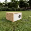 A wooden and styrofoam cat house sits on a grassy lawn with trees and bushes in the background. Produktbild-Vorschau
