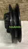 A black pulley is shown against a textured wooden background and a white surface. Produktbild-Vorschau