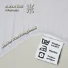 A close-up of a white fitted sheet showing its elastic edge and care instructions. Produktbild-Vorschau