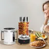 A woman is smiling while looking at a vertical electric grill with meat skewers, placed on a table with breakfast items. Náhled obrázku produktu