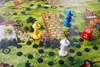A board game set in a fairytale forest with colorful pawns and a die. Produktbild-Vorschau